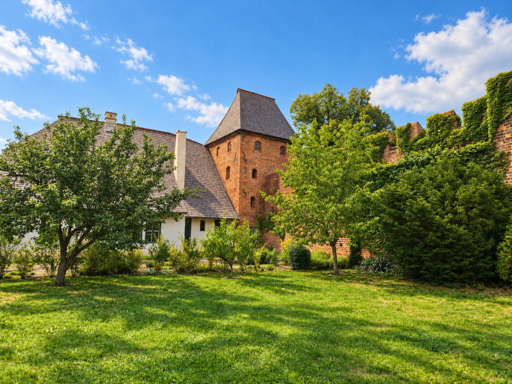 Old Deanery with a tiled roof beside the brick Kaplanka tower in Nymburk.
